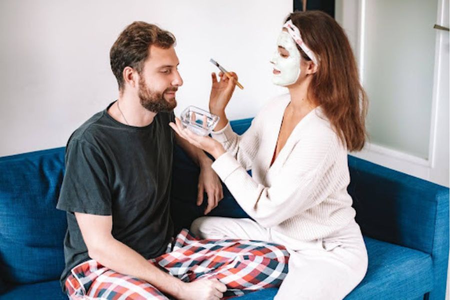 Coppia sul divano mentre lui riceve una maschera viso