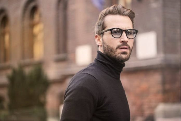 Uomo con dolcevita nero e occhiali in città